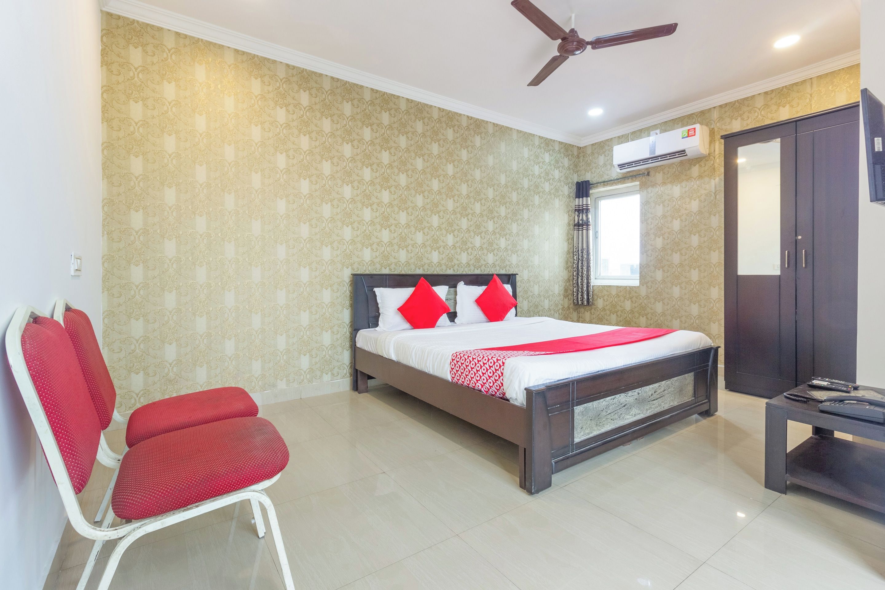 Habitación de hotel con cama, una silla, un escritorio y un ventilador de techo.