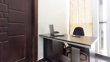 Una habitación con escritorio, silla, laptop y teléfono.