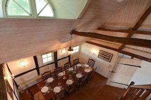 A dining area with a high ceiling, wooden beams, and a table set for six. - Holiday home in Gelting with swimming pool (Gelting)