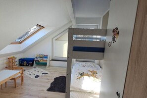 Un dormitorio infantil con literas, un escritorio y una ventana.