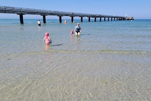 A pier extending into calm waters with people walking and swimming. - Holiday apartment with 3 bedrooms (Schönberg (Holstein))