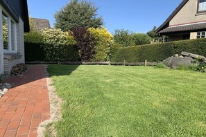 Une pelouse bien entretenue, avec un chemin en briques menant à une maison.
