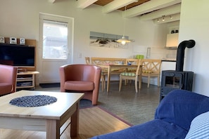 A living room with a TV, seating, a dining area, and a kitchen with a stove. - Holiday home in Langholz with swimming pool (Langholz)