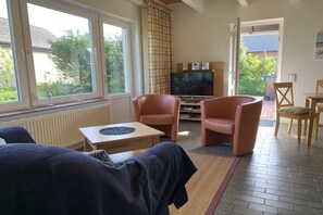 A living room with a TV, two leather chairs, a coffee table, and a view of the outdoors. - Holiday home in Langholz with swimming pool (Langholz)