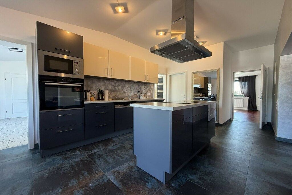 Una cocina moderna con armarios oscuros, una isla central y electrodomésticos integrados.