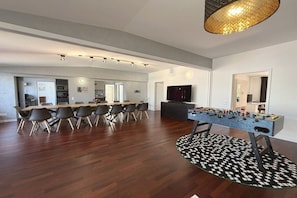 Ein modernes Wohnzimmer mit Essbereich, einem Kicker und einem Fernseher.