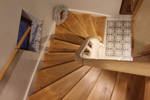 A wooden staircase with a white chair at the top. - Holiday home "Mittenmang" (Schleswig)