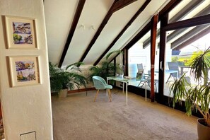 Une pièce avec un plafond en pente, un bureau avec une chaise et deux tableaux encadrés accrochés au mur.