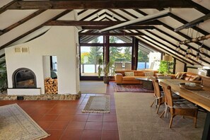 An interior with a fireplace, a sofa set, a dining table with chairs, and large windows. - Exclusive holiday apartment with views of the Harz Mountains (Goslar)