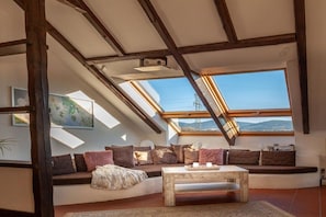 A loft-style room with a sloped ceiling, a sofa set, a coffee table, and a skylight. - Exclusive holiday apartment with views of the Harz Mountains (Goslar)