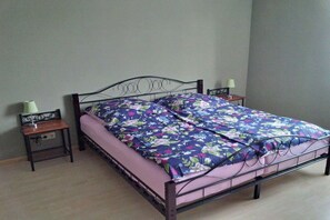 A single bed with a metal frame, a floral bedspread, and two bedside tables with lamps. - Holiday apartment with 2 bedrooms (Panker\/ Gadendorf)