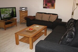 A living room with a television, wooden coffee table, and a sofa. - Andreas-Dirks-Straße 1 (Westerland)