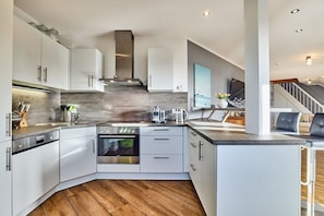 Een moderne keuken met witte kasten, een inbouwoven en een roestvrijstalen afzuigkap.
