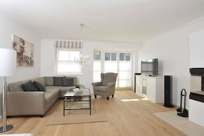 Ein modernes Wohnzimmer mit Sofa, Sessel und TV-Möbel.