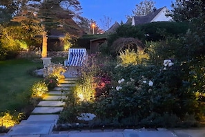 A garden pathway leading to a house with a small shed and a bench. - Stylish 3-room holiday apartment "City Oasis" (Westerland)