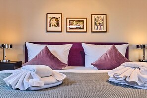 Ein Hotelzimmer mit einem Bett, zwei Kissen, einer Decke und drei gerahmten Bildern an der Wand.