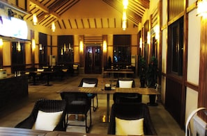 An indoor dining area with tables and chairs, wooden beams on the ceiling, and large windows. - ningbohangzhouwanhaidiwenquanjiudian (Ningbo)