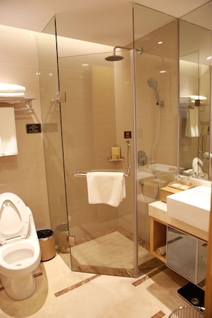A modern bathroom with a glass-enclosed shower, a toilet, and a sink with a mirror. - ningbohangzhouwanhaidiwenquanjiudian (Ningbo)
