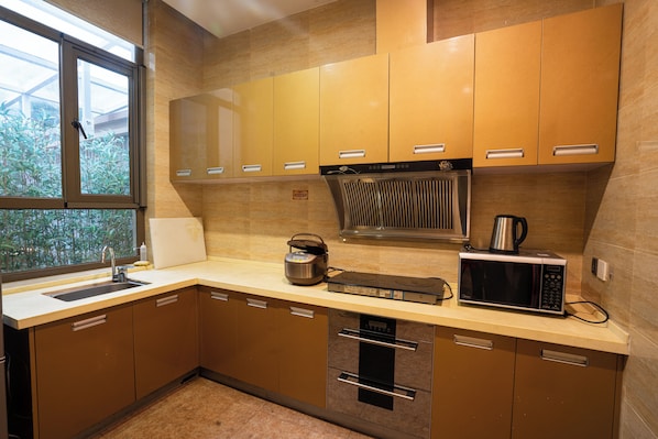 A modern kitchen with stainless steel appliances, wooden cabinets, and a window providing natural light.