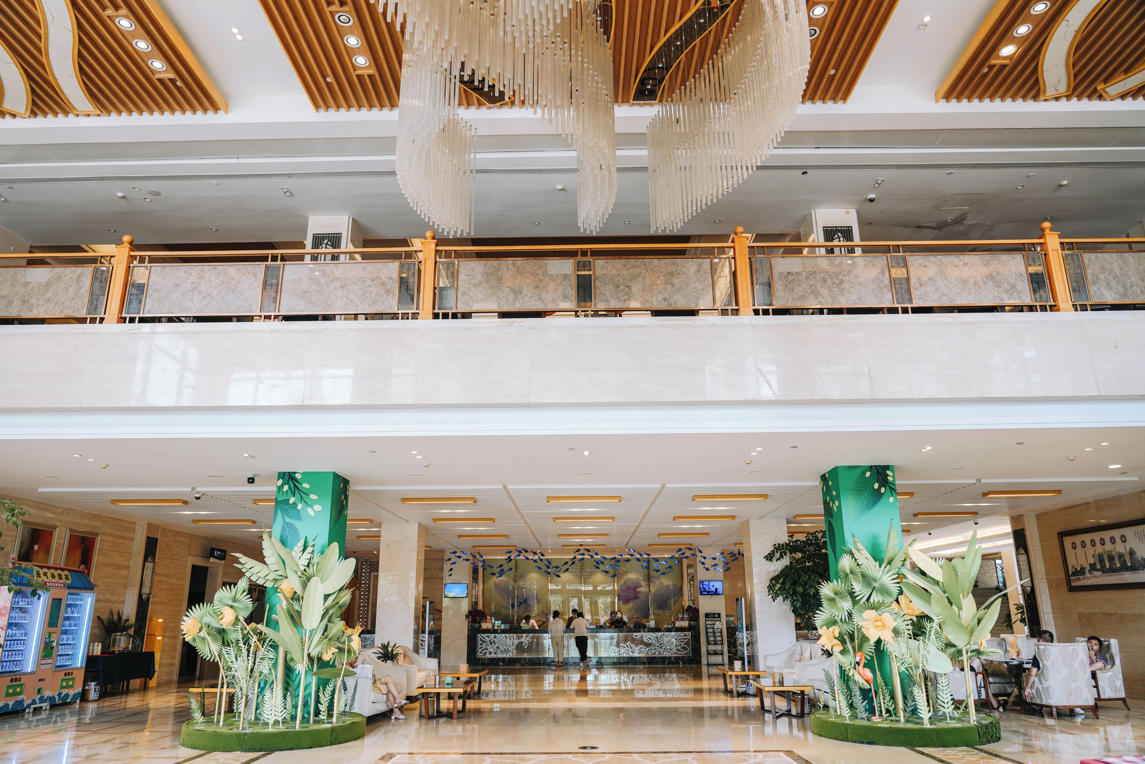 A hotel lobby with a reception desk, seating area, and a decorative plant display.