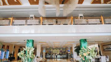 A hotel lobby with a reception desk, seating area, and a decorative plant display.
