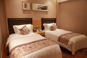 A hotel room with two beds, each with a headboard, a bedside table with a phone, and a wall-mounted clock. - ningbohangzhouwanhaidiwenquanjiudian (Ningbo)