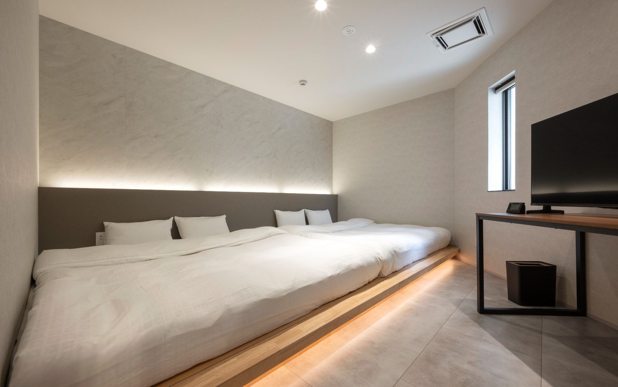 A modern hotel room with a large bed, a television, and a window.