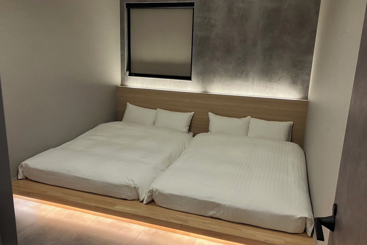 Una cama doble con cabecera de madera, una mesita de noche y una lámpara fijada a la pared.