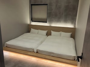 Una cama doble con cabecera de madera, una mesita de noche y una lámpara fijada a la pared.