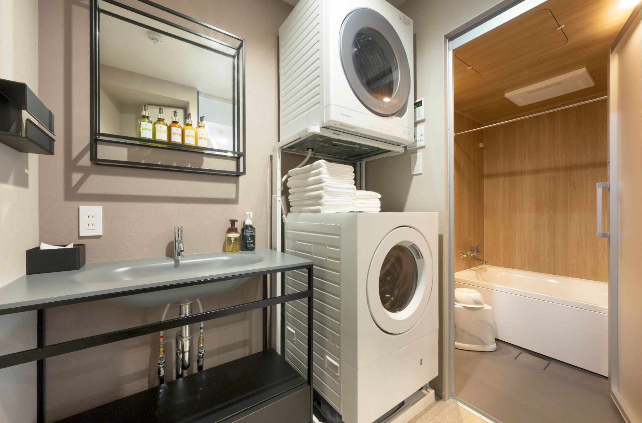 A modern bathroom with a built-in washing machine, a sink, and a mirror.