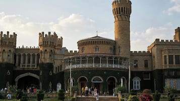 A historic building with a central tower, arched windows, and a courtyard with visitors.