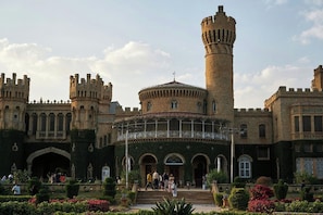 Un edificio histórico con una torre central, ventanas en arco y un patio con visitantes.