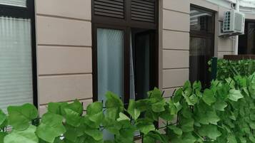 A building with a beige exterior, a window with a curtain, and an air conditioning unit mounted on the wall.