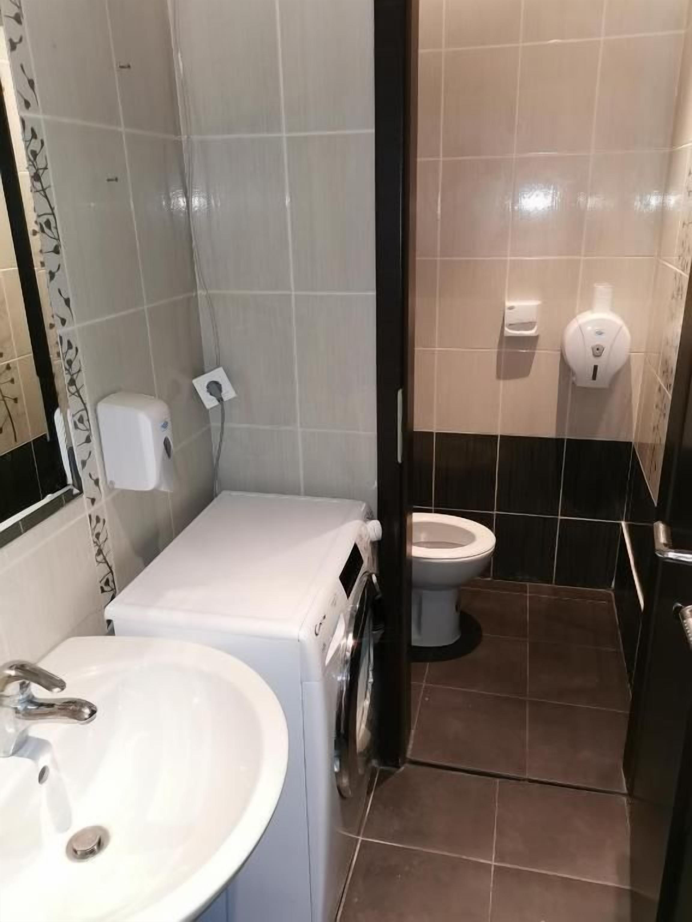 A bathroom with a sink, toilet, and washing machine.