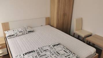 A bed with a quilted mattress and a headboard, a bedside table, and a bench.