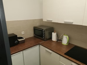 A compact kitchen with a microwave, kettle, and a small basket on the countertop. - Portofino Apartment (Izola)