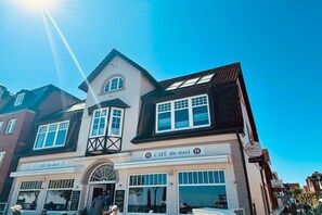 Um edifício de dois andares com um café chamado 'CAFÉ die insel' no andar térreo.