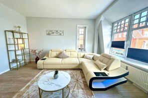 Uma sala de estar moderna com um sofá seccional, uma mesa de centro redonda e um aparador de vidro.