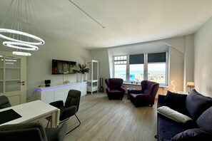 Ein modernes Wohnzimmer mit Essbereich, einer Küche und einem großen Fenster mit Blick.