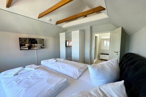 A hotel room with a bed, a television, and a wardrobe. - House with sea view - Apt. 4 (Wyk auf Föhr)