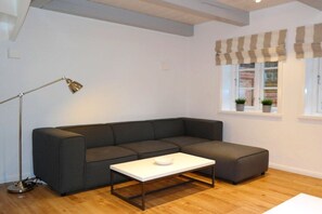 A modern living room with a dark grey sofa, a white coffee table, a floor lamp, and a window with striped valance. - 5 Martinique at the Boldix House (Wyk-Boldixum)