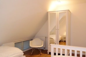 A bedroom with a white bed, a white chair, a white wardrobe, and a sloped ceiling. - 5 Martinique at the Boldix House (Wyk-Boldixum)