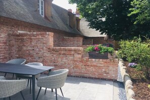 An outdoor patio with a brick wall, a table, and chairs. - 5 Martinique at the Boldix House (Wyk-Boldixum)