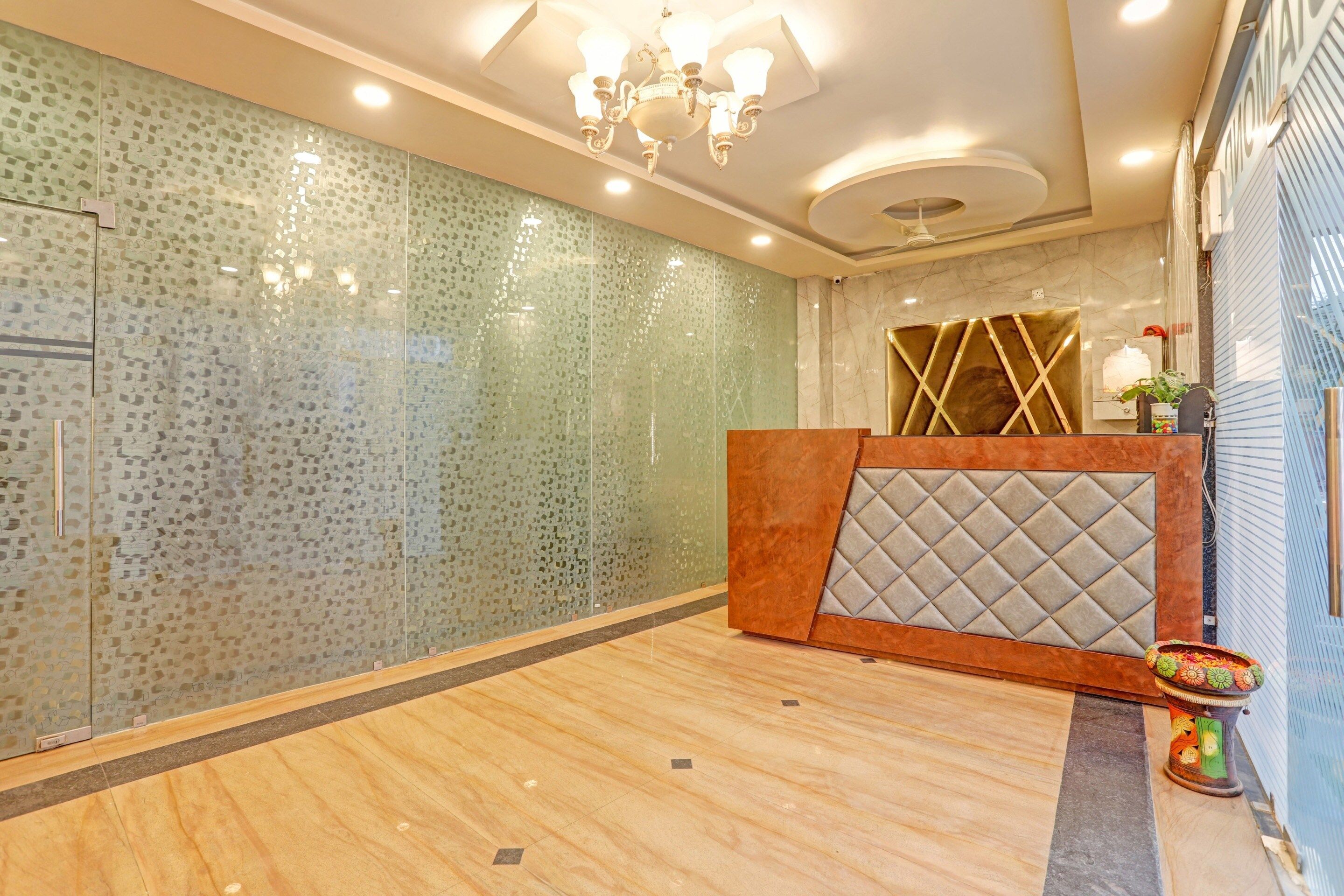 A reception area with a modern design, featuring a patterned wall, a wooden reception desk, and a chandelier.