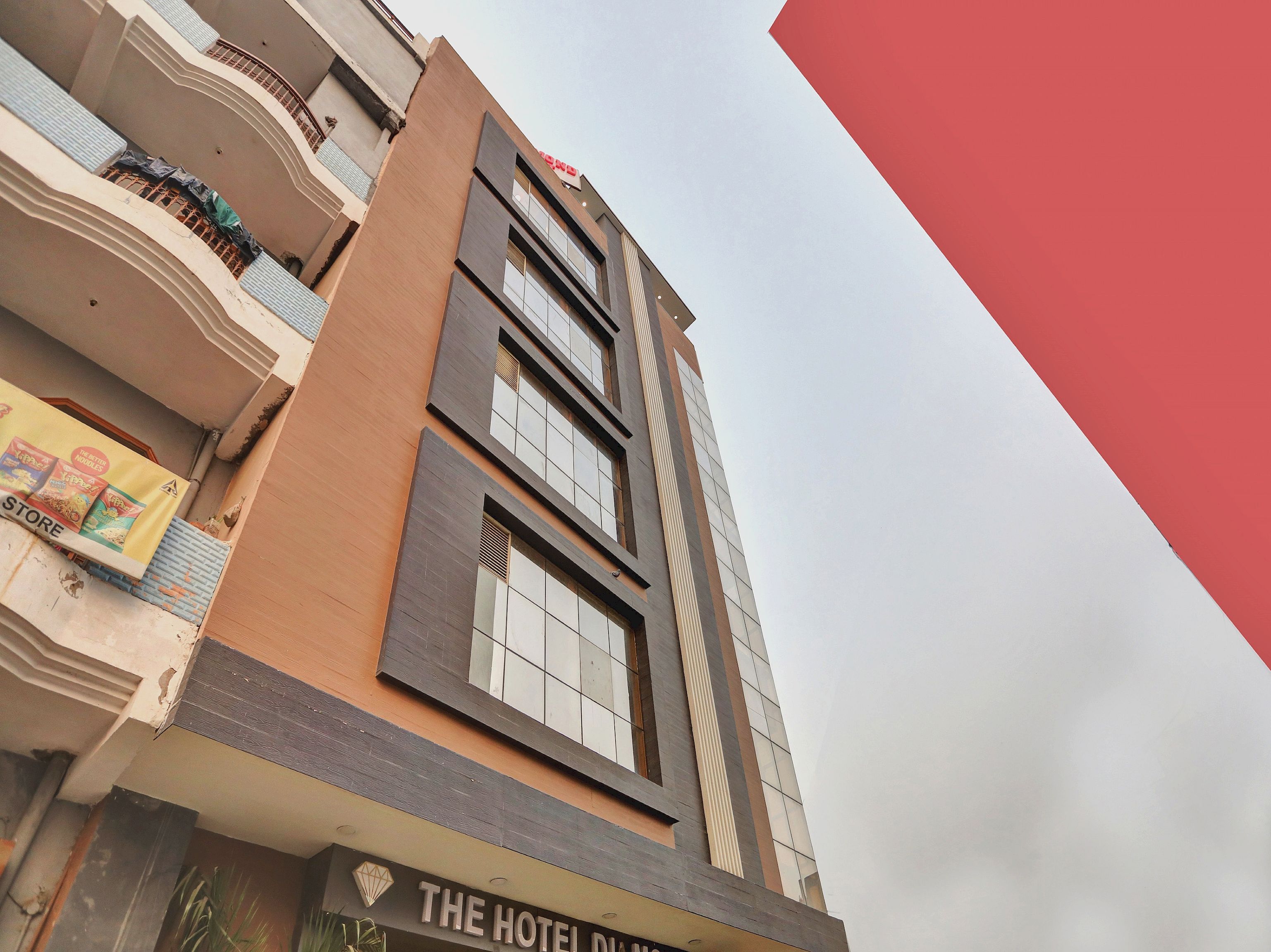A hotel building with multiple floors, balconies, and a sign indicating it is 'The Hotel Dili.'