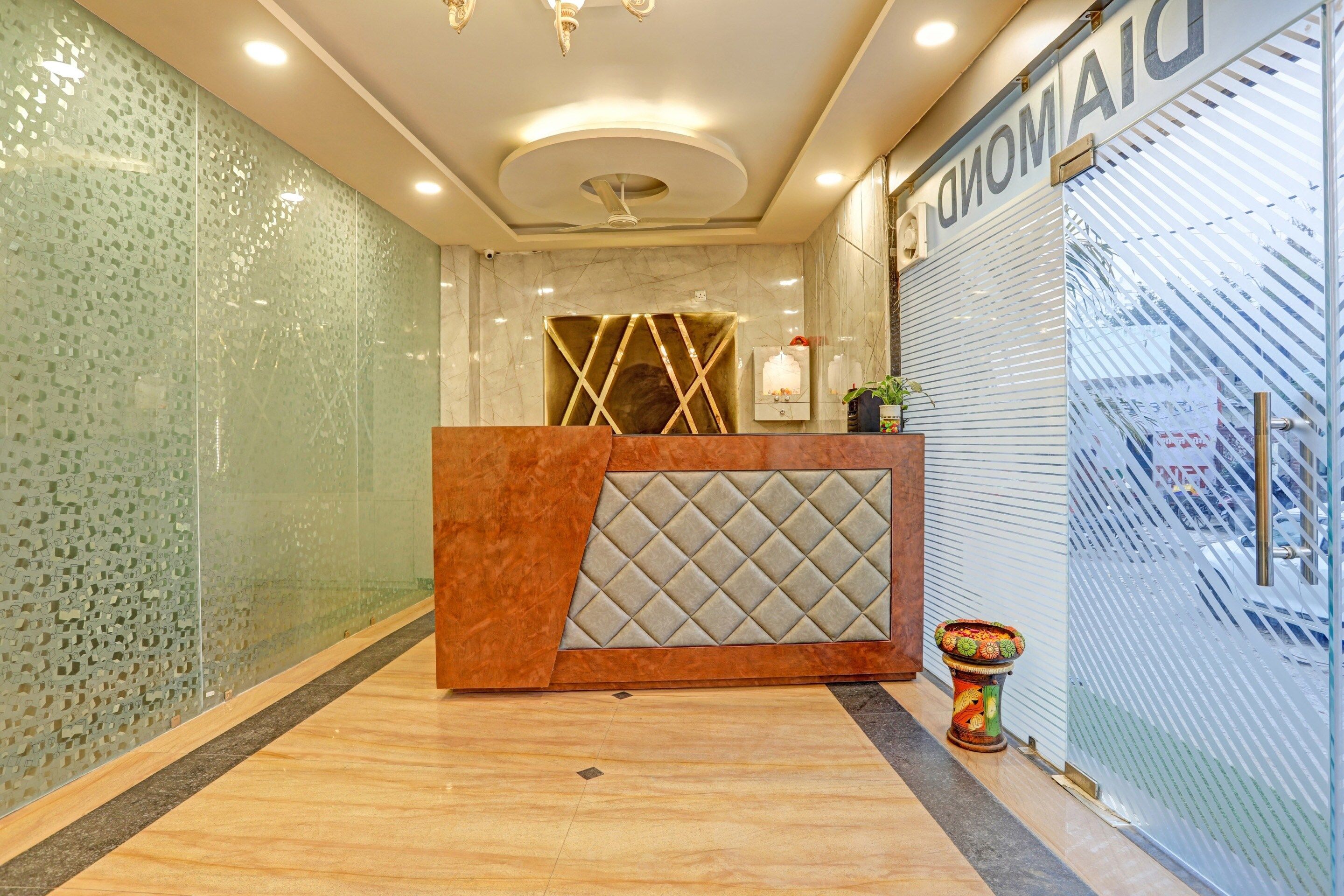 A reception area with a modern design, including a reception desk, a decorative plant, and a glass wall with a patterned design.