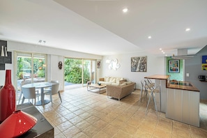 A spacious living area with a dining table, sofa, and kitchen bar. - Family Apartment With Pool & Garden 5 P - Cannes (Cannes)