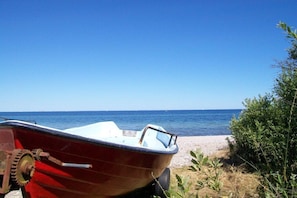 A boat parked on a beach with the sea in the background. - Helene's little house (Gelting)