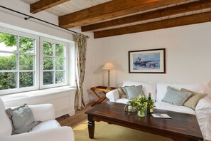 A room with a white sofa, a wooden coffee table, a lamp, and a framed picture on the wall. - Helene's little house (Gelting)