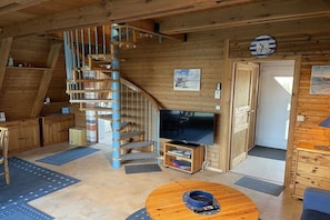 A wooden interior with a spiral staircase, a television, and a round coffee table. - Holiday home in Damp with swimming pool (Damp)